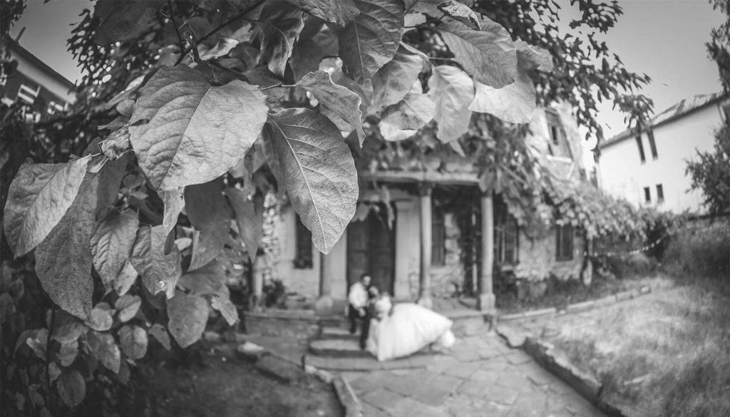 Elegant wedding couple outside a luxurious historic venue surrounded by lush greenery. Perfect setting for a high-end wedding celebration.