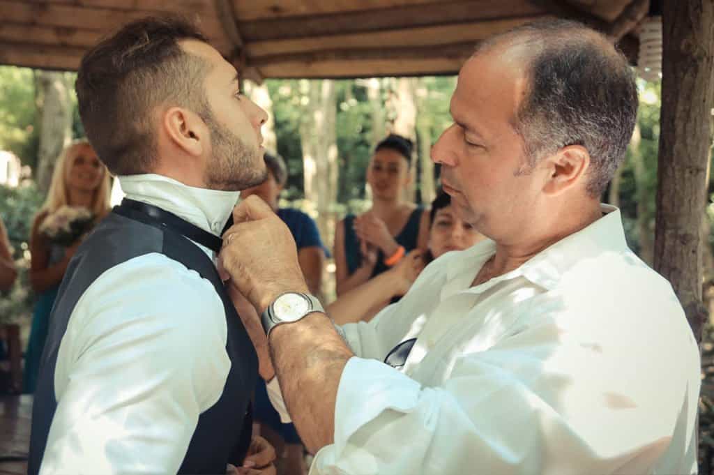 Elegant wedding moment with groom adjusting his tie at a luxury outdoor venue.