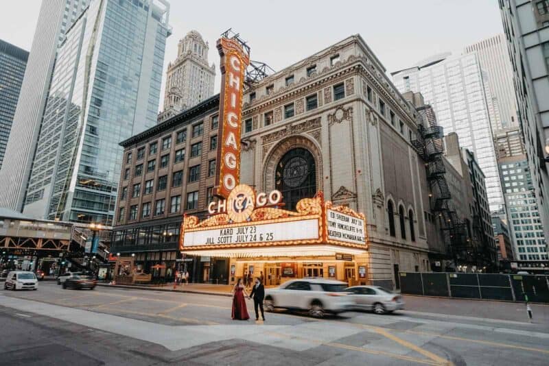 Elegant bride and groom holding hands outside Chicago Theater, a historic high-end venue for luxury wedding celebrations.