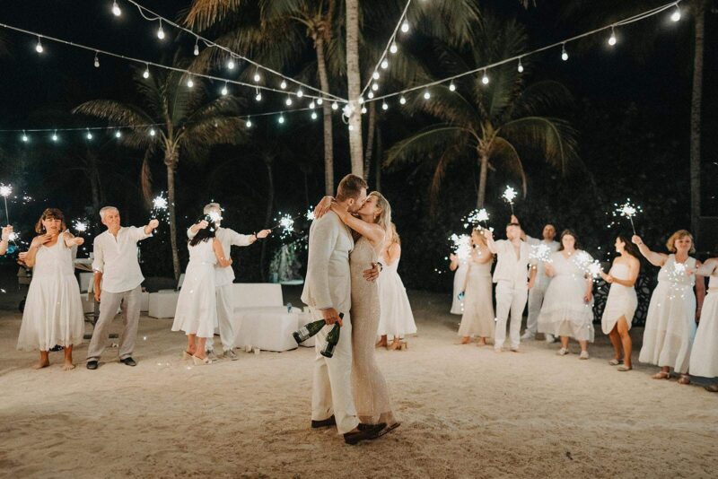 Sparkler send-off at a beach luxury wedding under string lights and palm trees.