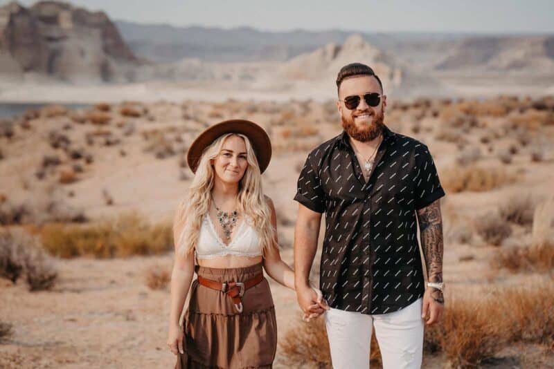Stylish couple holding hands in a desert landscape, perfect for luxury wedding planning and high-end venue inspiration.