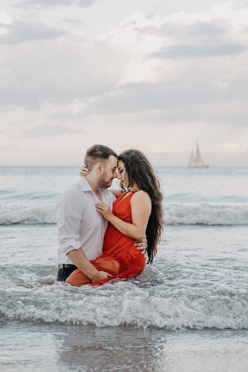 Elegant couple embracing in the ocean, perfect for luxury beachfront wedding photos.