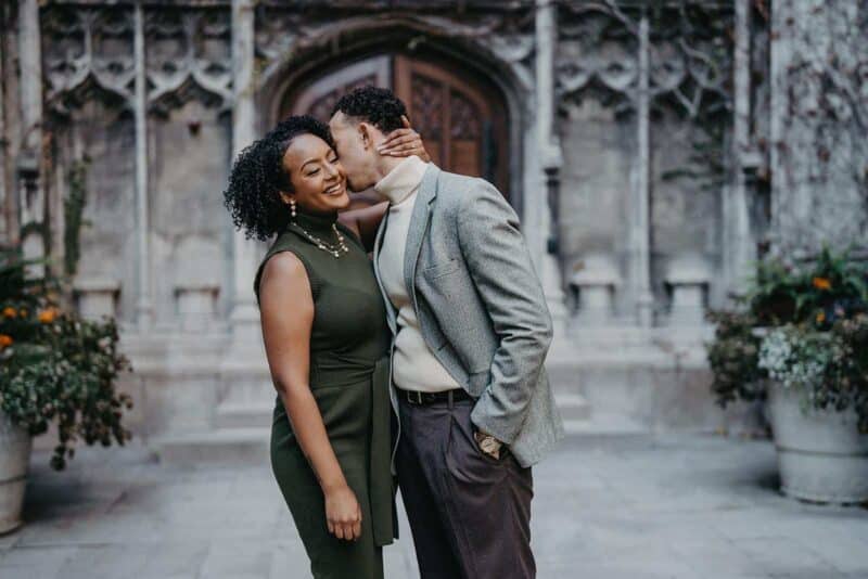Elegant couple sharing a tender moment at a luxury wedding venue with historic architecture and lush floral decor.