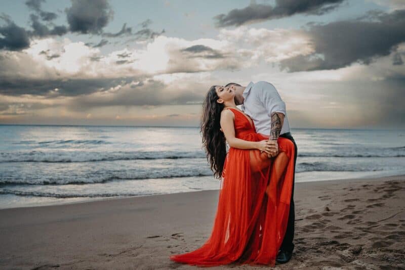 Romantic couple on the beach at sunset, elegant wedding attire, luxury wedding photography, high-end beachfront venue, stylish romance scene.