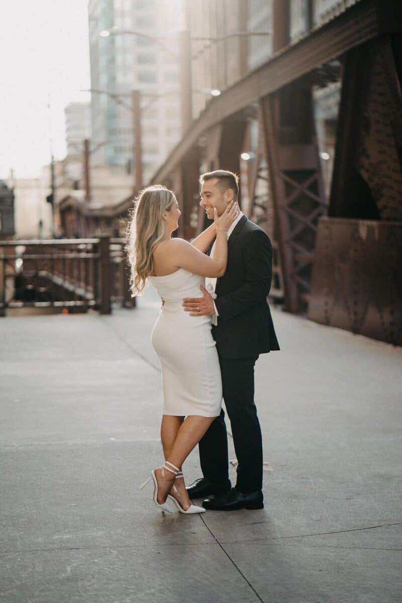 Elegant bride and groom sharing a romantic moment in downtown city during sunset.