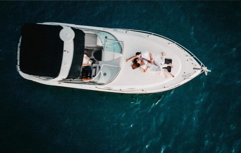 Luxurious yacht wedding ceremony with couple embracing on deck, overlooking deep blue ocean, perfect for high-end destination weddings.