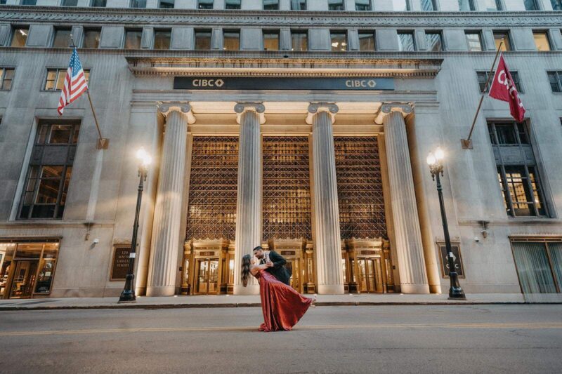 Elegant couple dancing in front of a grand, historic bank building, perfect for luxury wedding photoshoot.