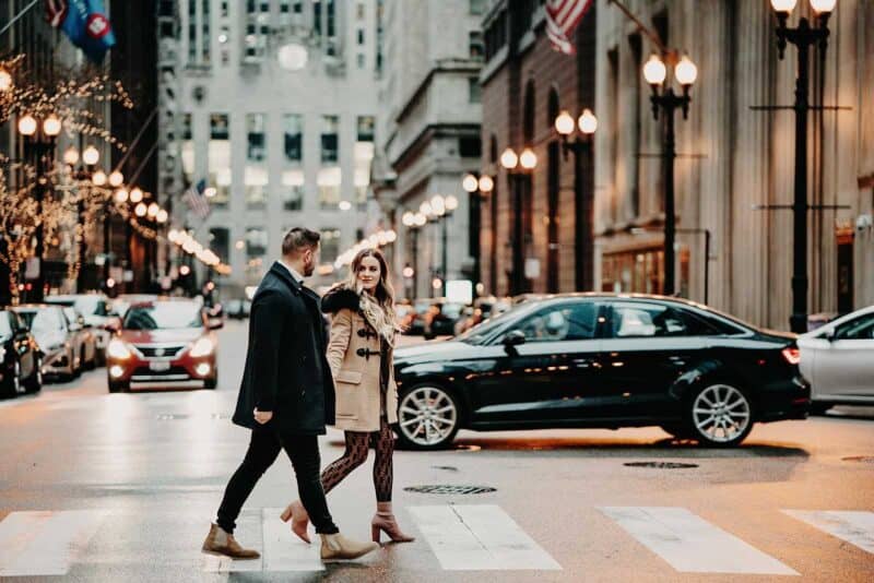 High-end couple walking on city street with elegant fashion and city lights, luxury lifestyle, urban sophistication, stylish fashion, romantic ambiance, modern aesthetic.