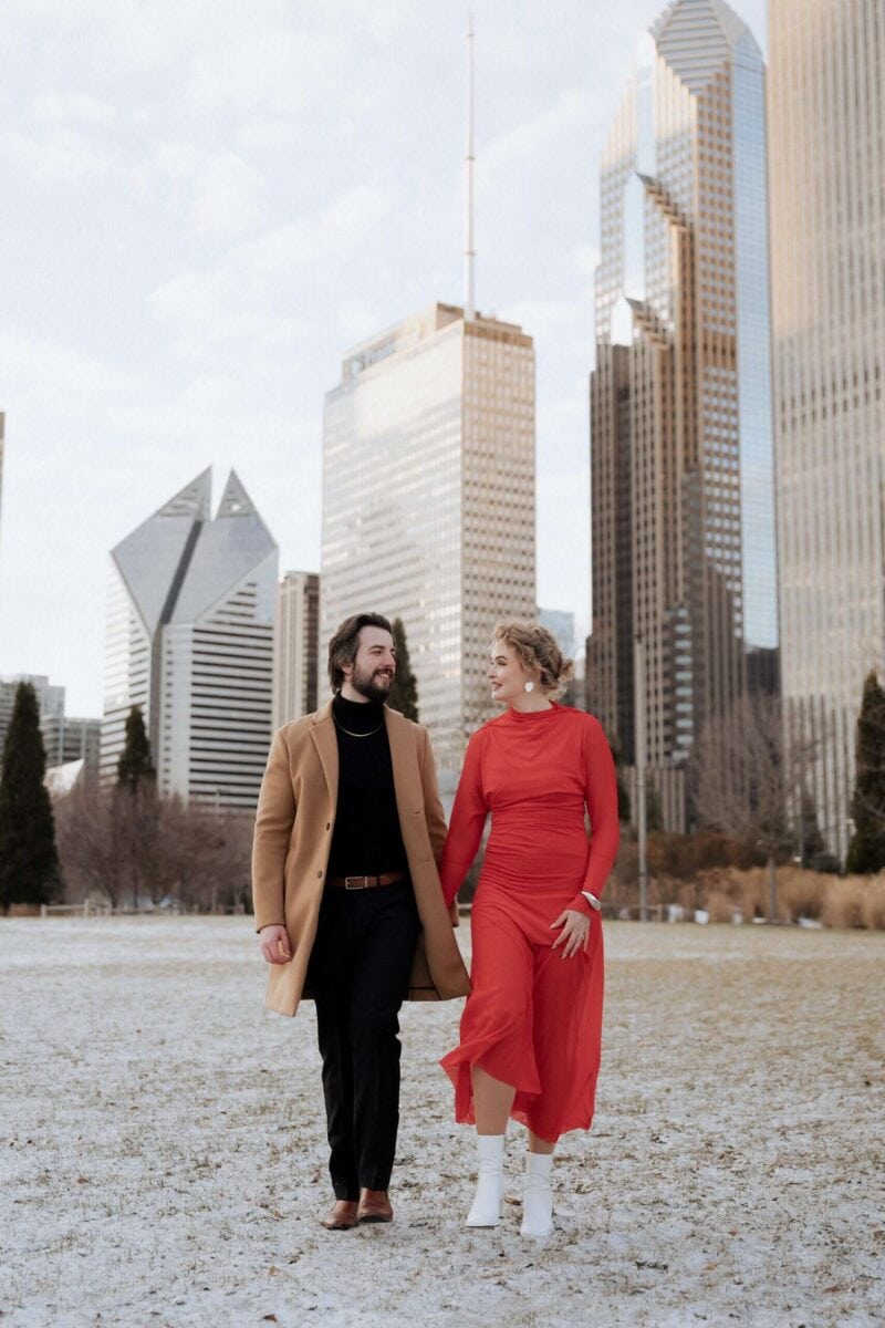 Elegant couple walking in urban park with city skyscrapers in background, capturing romantic luxury wedding moments.