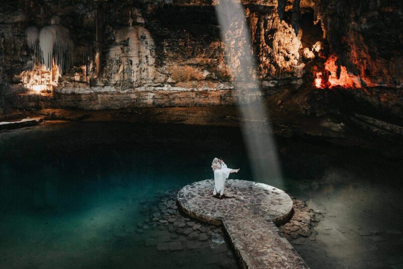 Romantic bride and groom wedding photoshoot at an underground cave with dramatic lighting and natural rock formations.