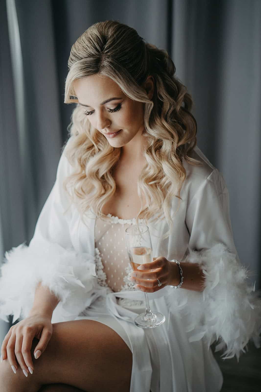 Luxury bride with elegant hairstyle holding champagne glass at high-end wedding venue.