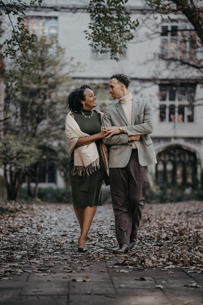 Elegant black and white couple in stylish fall fashion strolling in a romantic park setting.