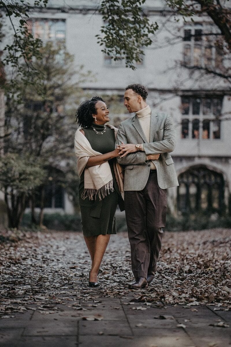 Elegant black and white couple in stylish fall fashion strolling in a romantic park setting.