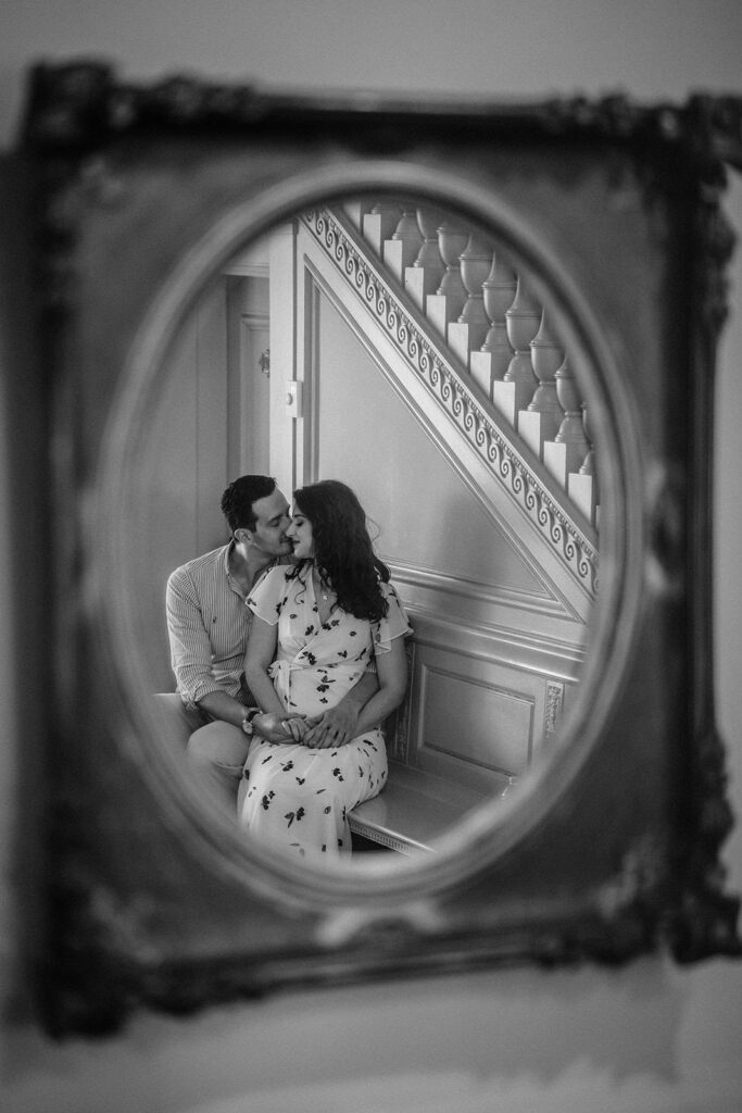 Elegant couple sharing a tender moment reflected in an ornate vintage mirror at a luxurious high-end wedding venue, showcasing romance and sophisticated decor.