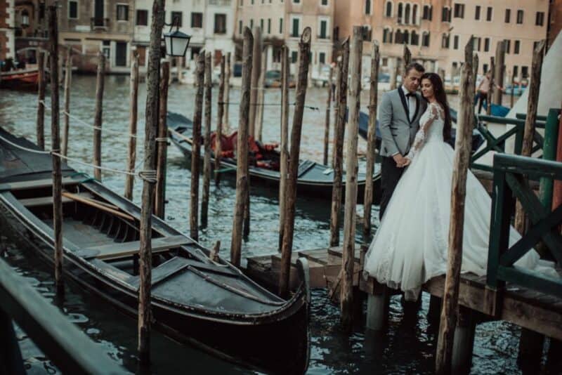 Venetian couple wedding by canal with gondolas and historic architecture in Italy.