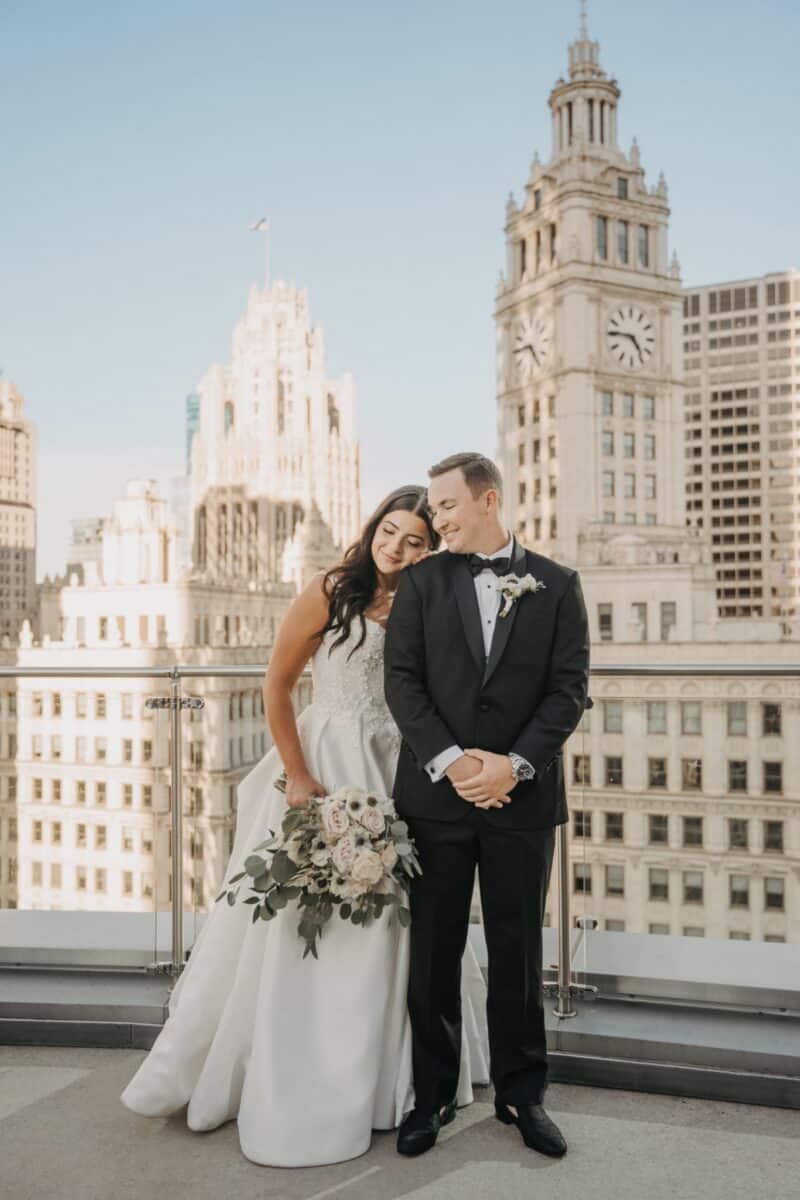 Elegant wedding couple on rooftop terrace with city skyline backdrop, perfect for luxury high-end wedding photography.