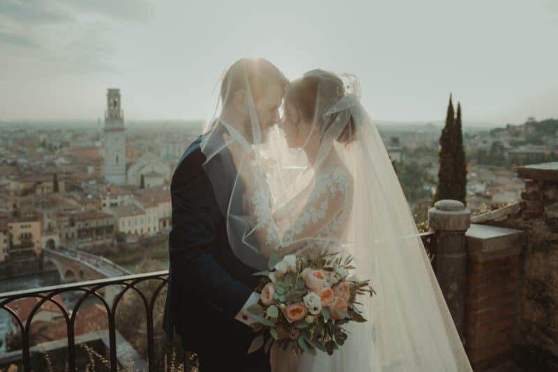 Elegant wedding couple on a scenic rooftop with historic city view, perfect for luxury wedding photography.