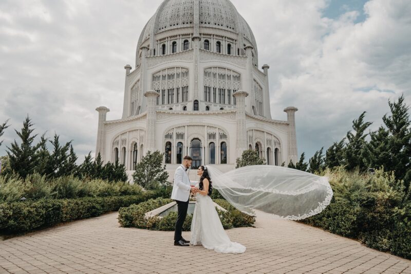 Majestic white wedding couple in front of iconic palace for luxurious wedding venue.