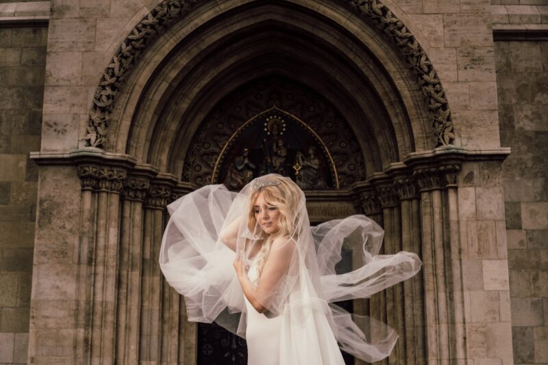 Elegant bride with flowing veil in a historic church for luxury wedding photography, showcasing high-end venue decor and sophisticated atmosphere.