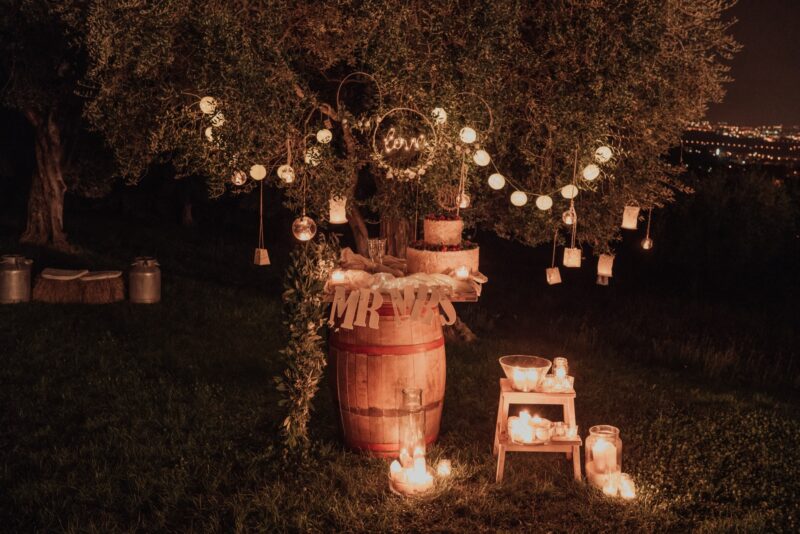 Luxury wedding outdoor night celebration with romantic candlelit decor and string lights in a natural setting.