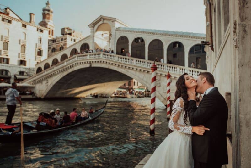 Venetian canal wedding photography showcasing a romantic couple by the water near the Rialto Bridge, capturing luxury wedding moments in Venice.
