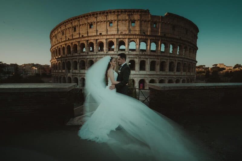 Elegant bride and groom portrait at sunset with the Colosseum as a historic backdrop, capturing a romantic moment during their luxury wedding shoot in Rome.