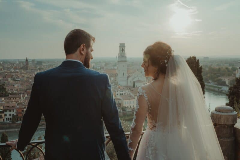 Elegant bride and groom overlooking historic Italian cityscape at sunset, capturing luxurious wedding moment.