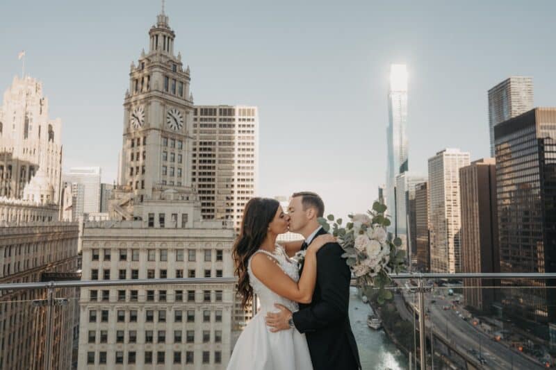 Elegant bride and groom sharing a kiss on a rooftop with iconic city skyline, perfect for luxury wedding photography.