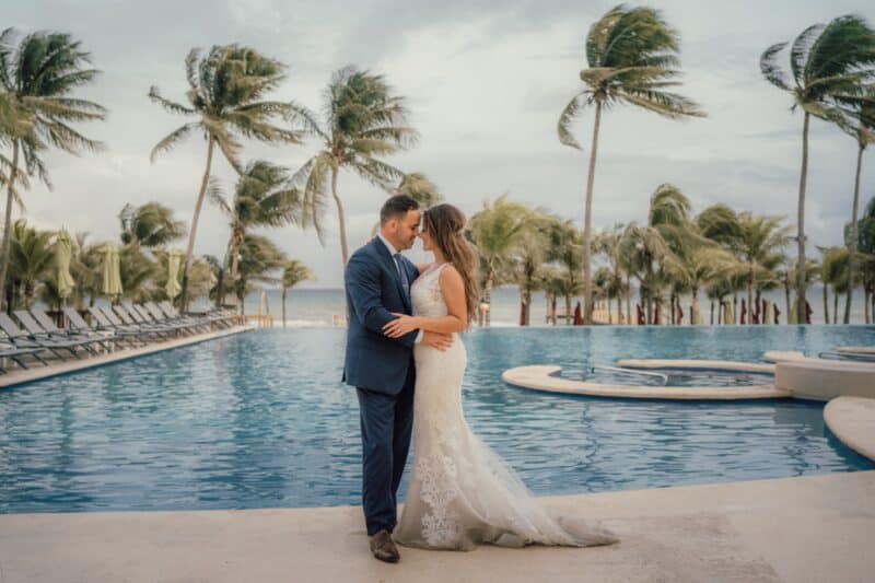 Luxury couple wedding by infinity pool with tropical palm trees at high-end seaside resort.