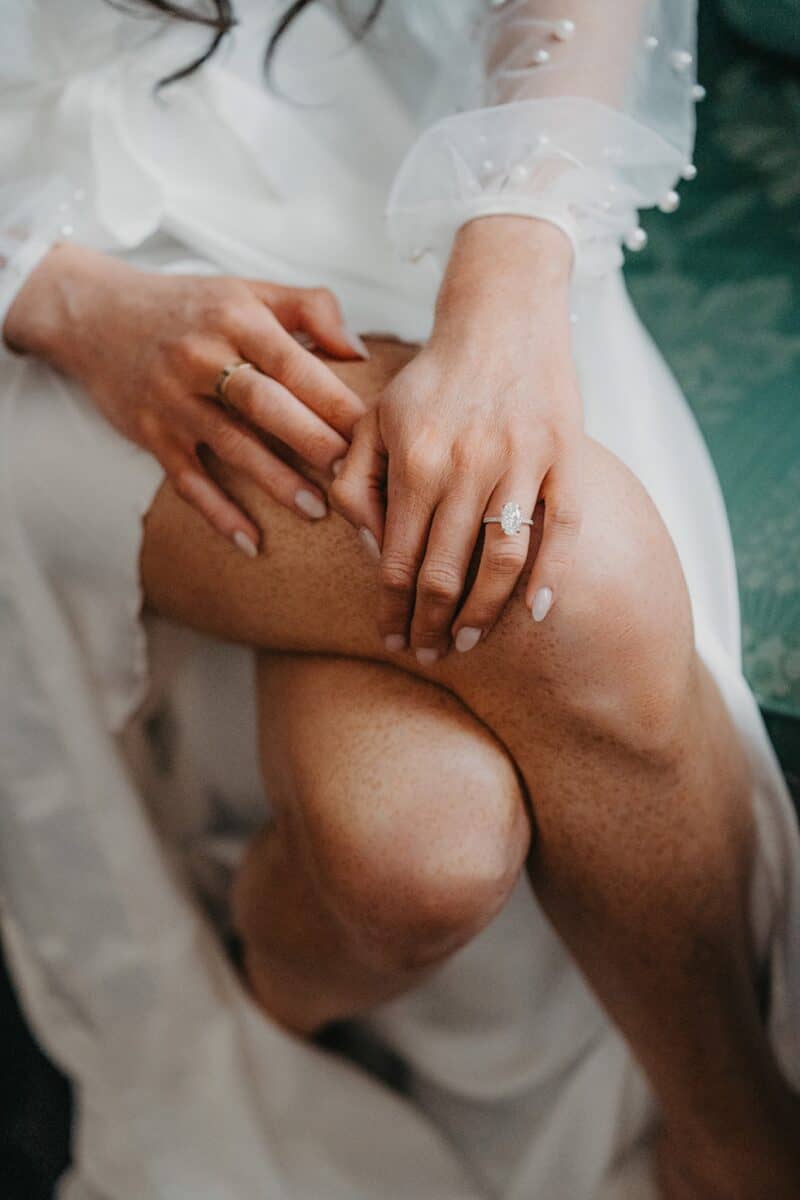 Luxury wedding rings and delicate hand details on bride's leg, close-up shot.