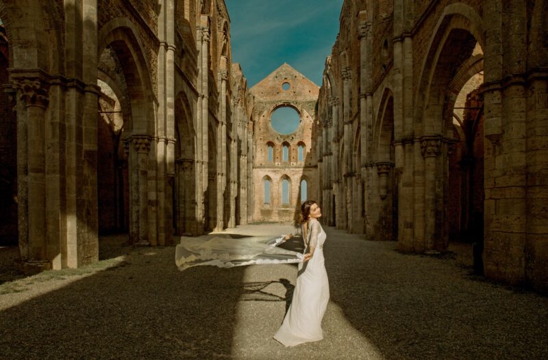 Elegant bride in a flowing wedding gown at a historic, architecturally stunning ruins venue, perfect for luxury wedding celebrations.