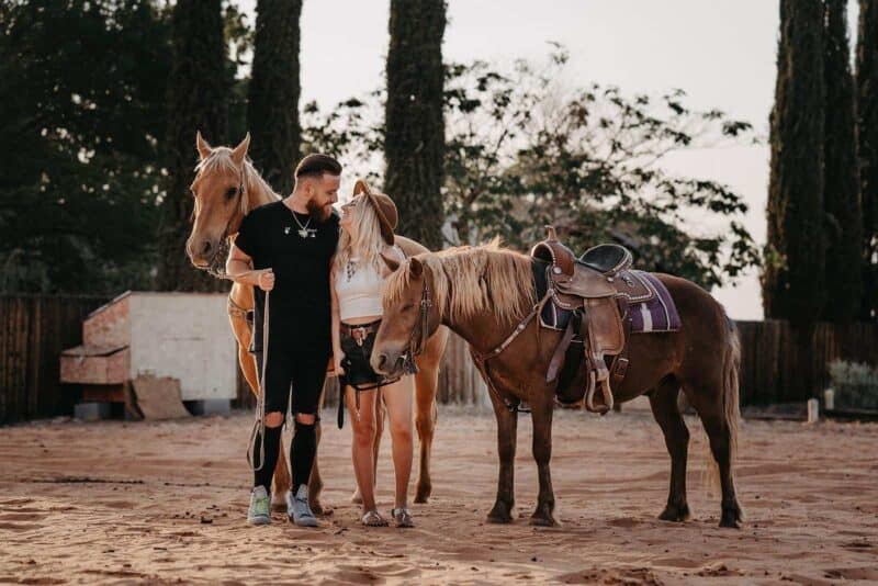 Elegant couple with horses at a luxurious outdoor wedding venue, capturing romantic moments surrounded by nature.