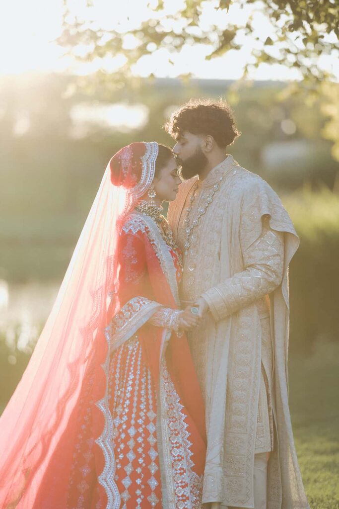 Elegant wedding couple in traditional attire, outdoors at sunset, celebrating a luxurious wedding ceremony.