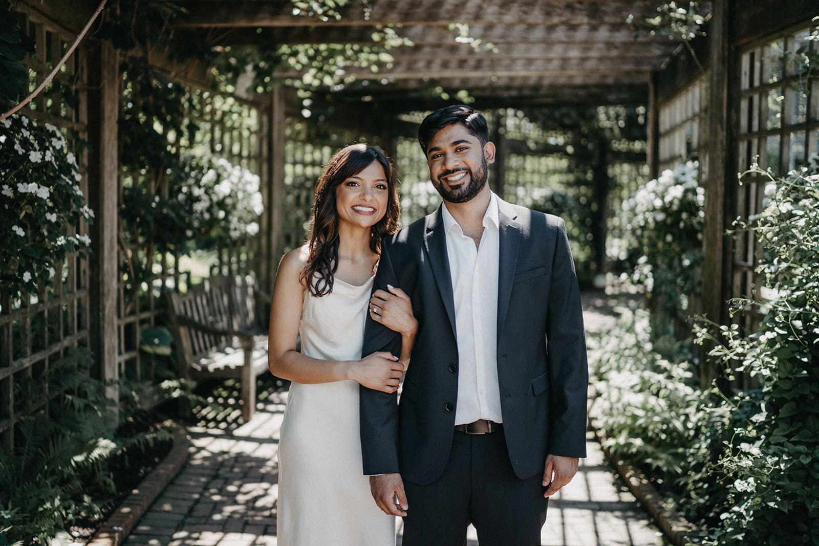 Elegant engaged couple smiling at a luxurious garden wedding venue.
