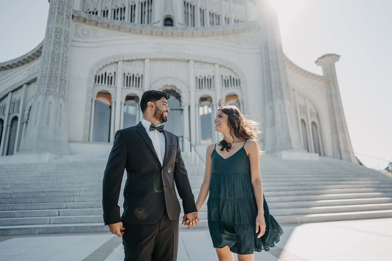 Elegant couple holding hands outside a stunning white high-end wedding venue, emphasizing luxury wedding photography.