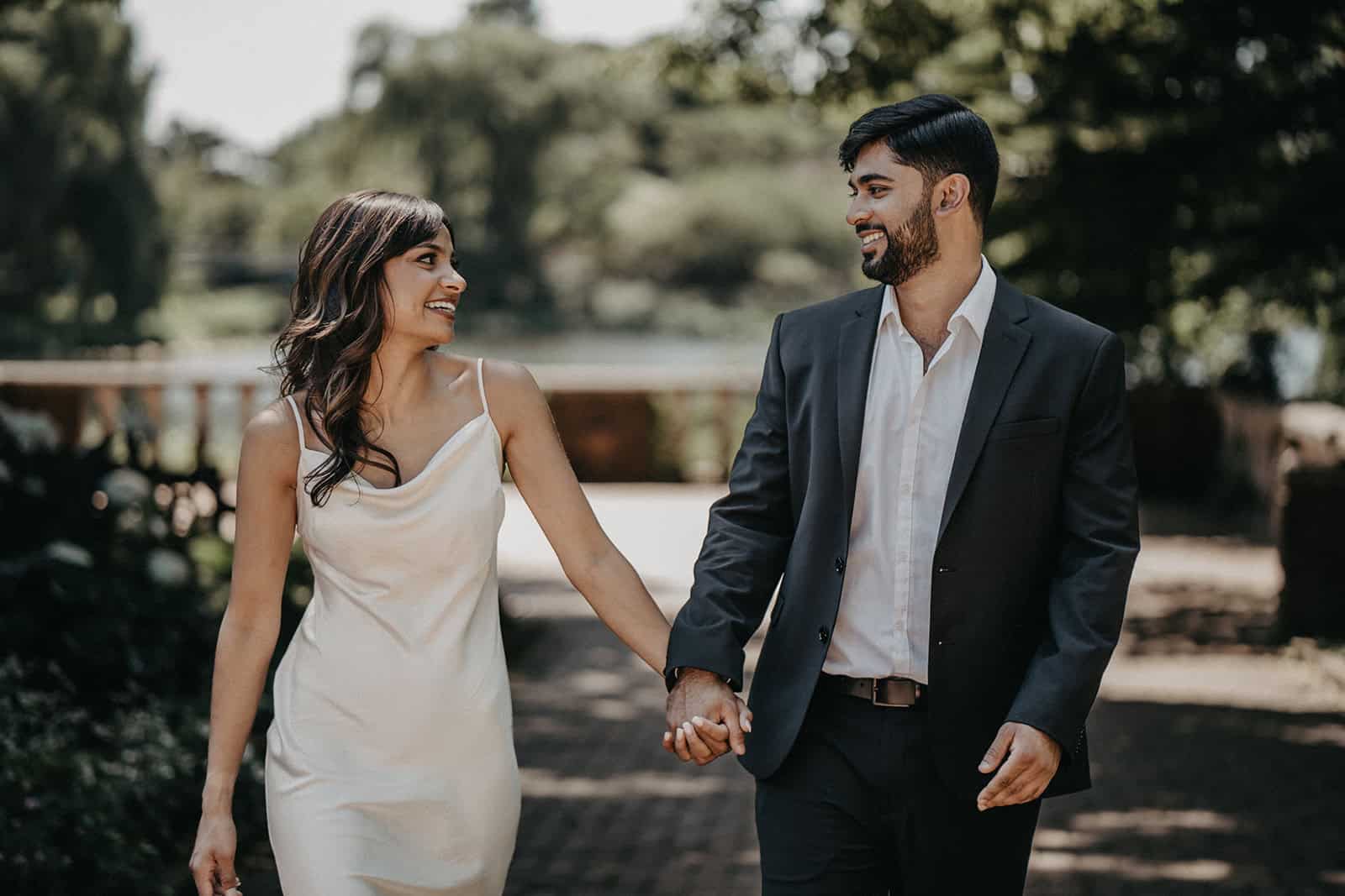 Romantic couple holding hands outdoors at a luxurious wedding venue.
