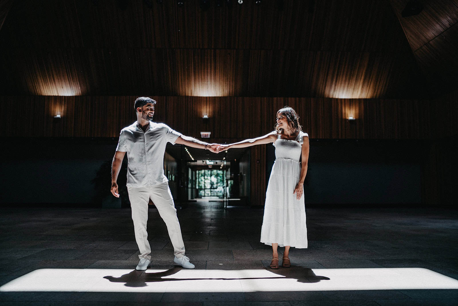 Elegant bride and groom sharing a dance in a luxurious, modern venue with wooden interior at a high-end wedding celebration.
