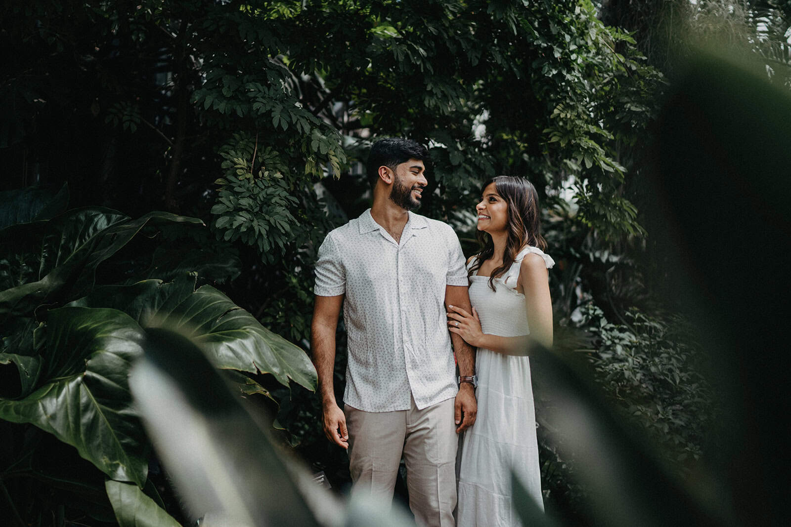 Luxurious couple enjoying a romantic moment in a lush, tropical garden setting, ideal for high-end wedding photography.
