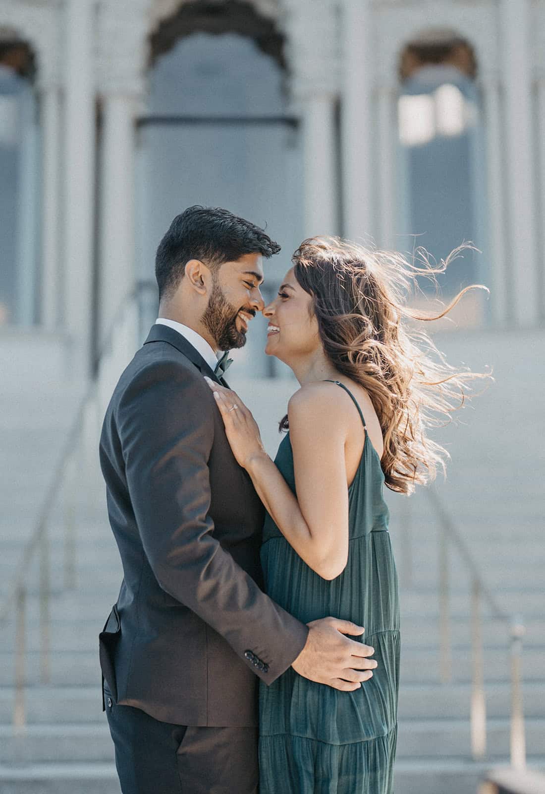 Elegant bride and groom share a romantic moment outdoors in front of a historic building, capturing the essence of luxury wedding photography.