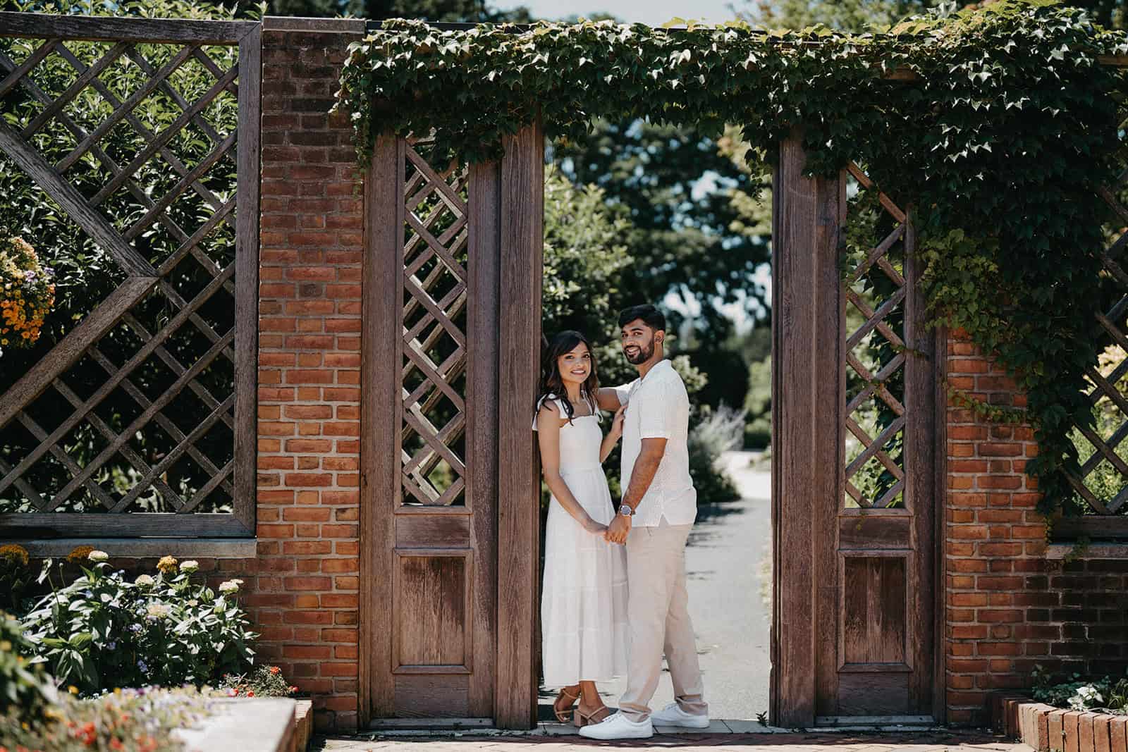 Elegant couple posing in a picturesque garden setting for a luxury wedding photoshoot.
