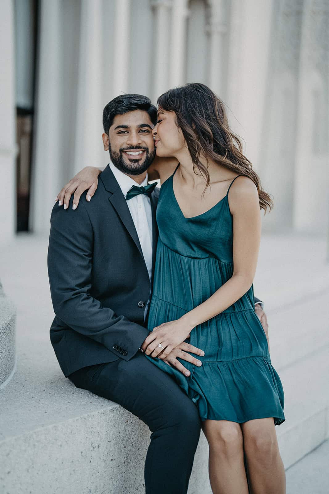 Elegant couple in formal attire sharing a romantic moment outdoors at a luxury wedding venue.