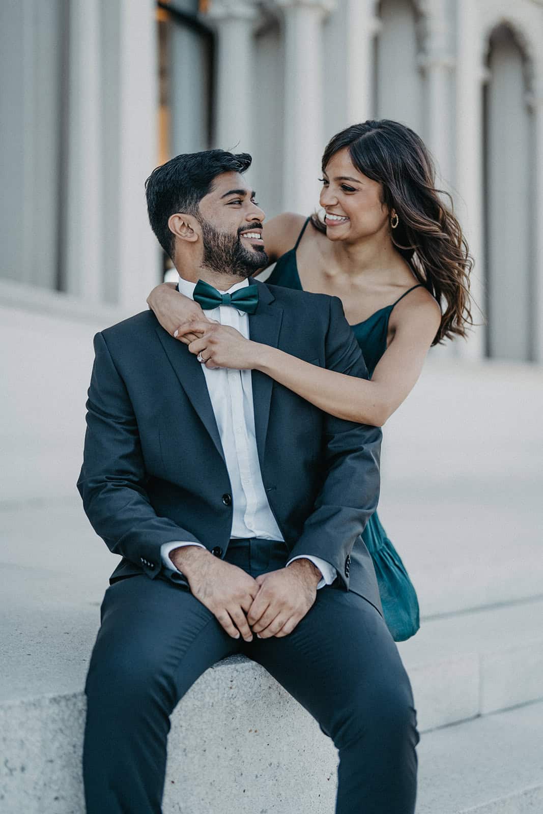 Elegant couple in formal attire sharing joyful moment outdoors at luxury wedding venue.