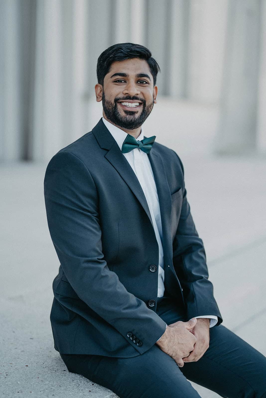 Elegant groom in classic tuxedo with bow tie at luxury wedding venue.
