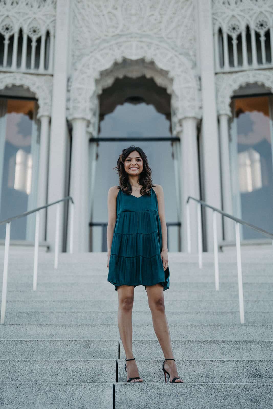 Elegant woman in blue dress standing on grand staircase at luxury wedding venue.