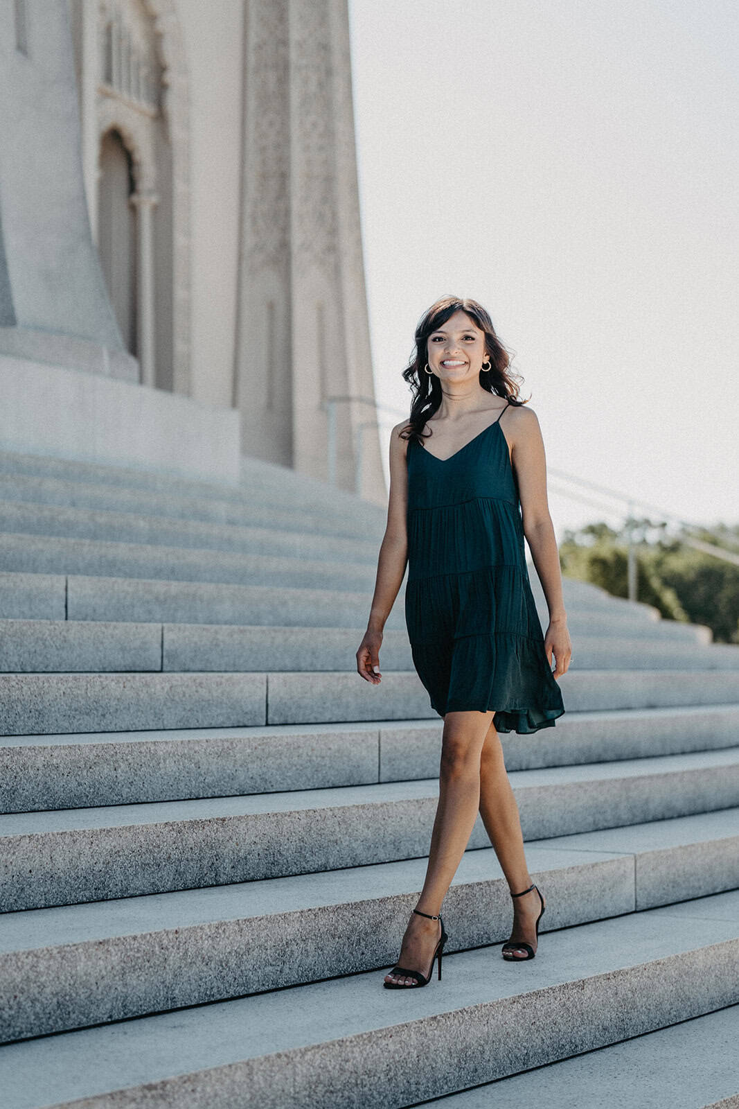 Elegant woman in a navy dress on grand staircase at luxury wedding venue.