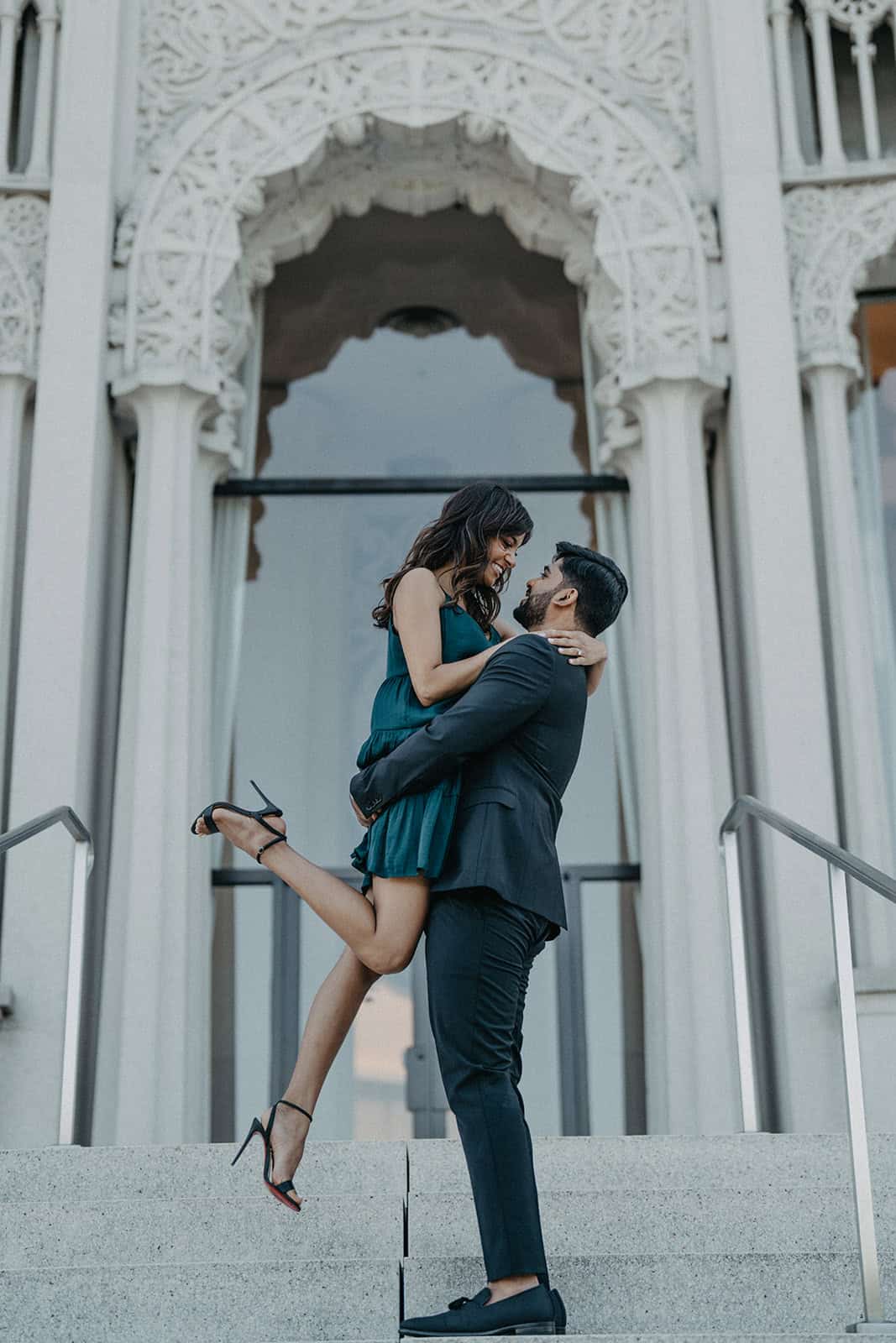 Luxury wedding couple outside ornate high-end venue.