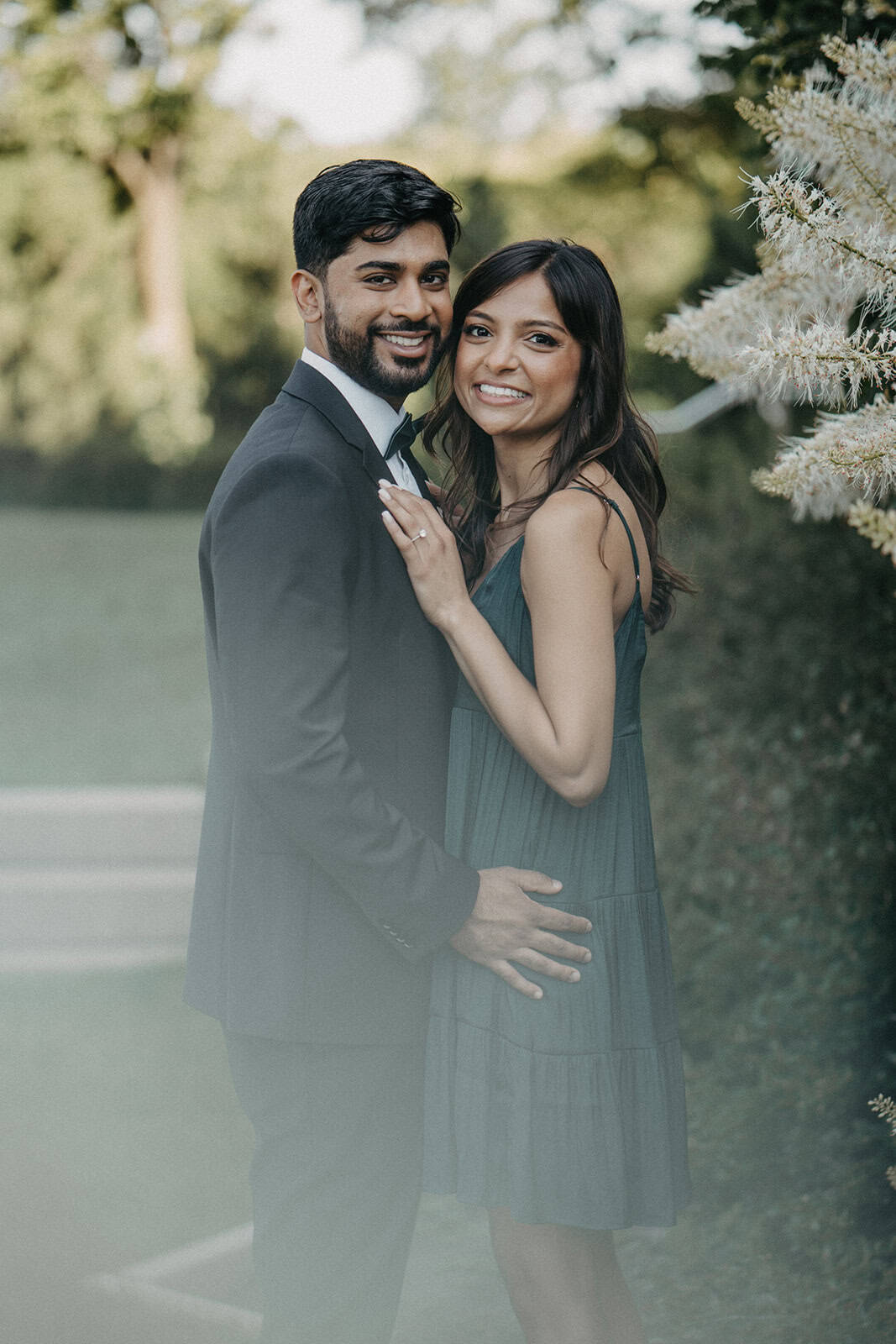 Elegant couple in formal attire at luxury outdoor wedding setting with lush greenery.