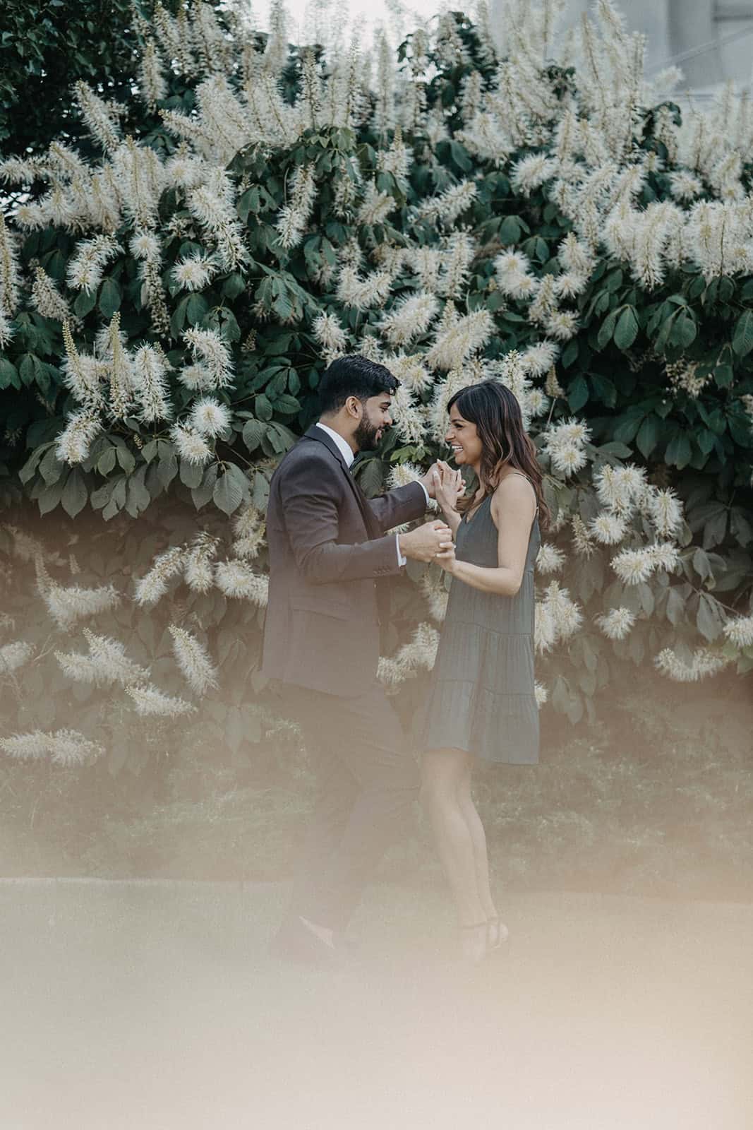 Elegant couple exchanging vows amidst lush greenery and white floral backdrop at a luxury outdoor wedding venue.