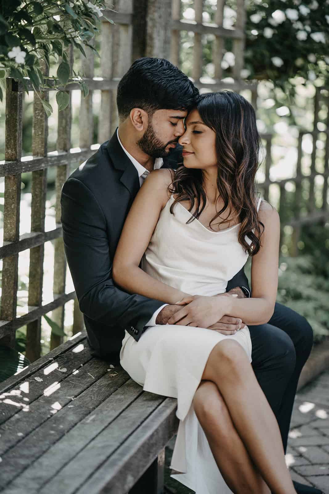 Elegant couple embracing in a romantic outdoor setting for a luxury wedding photoshoot.