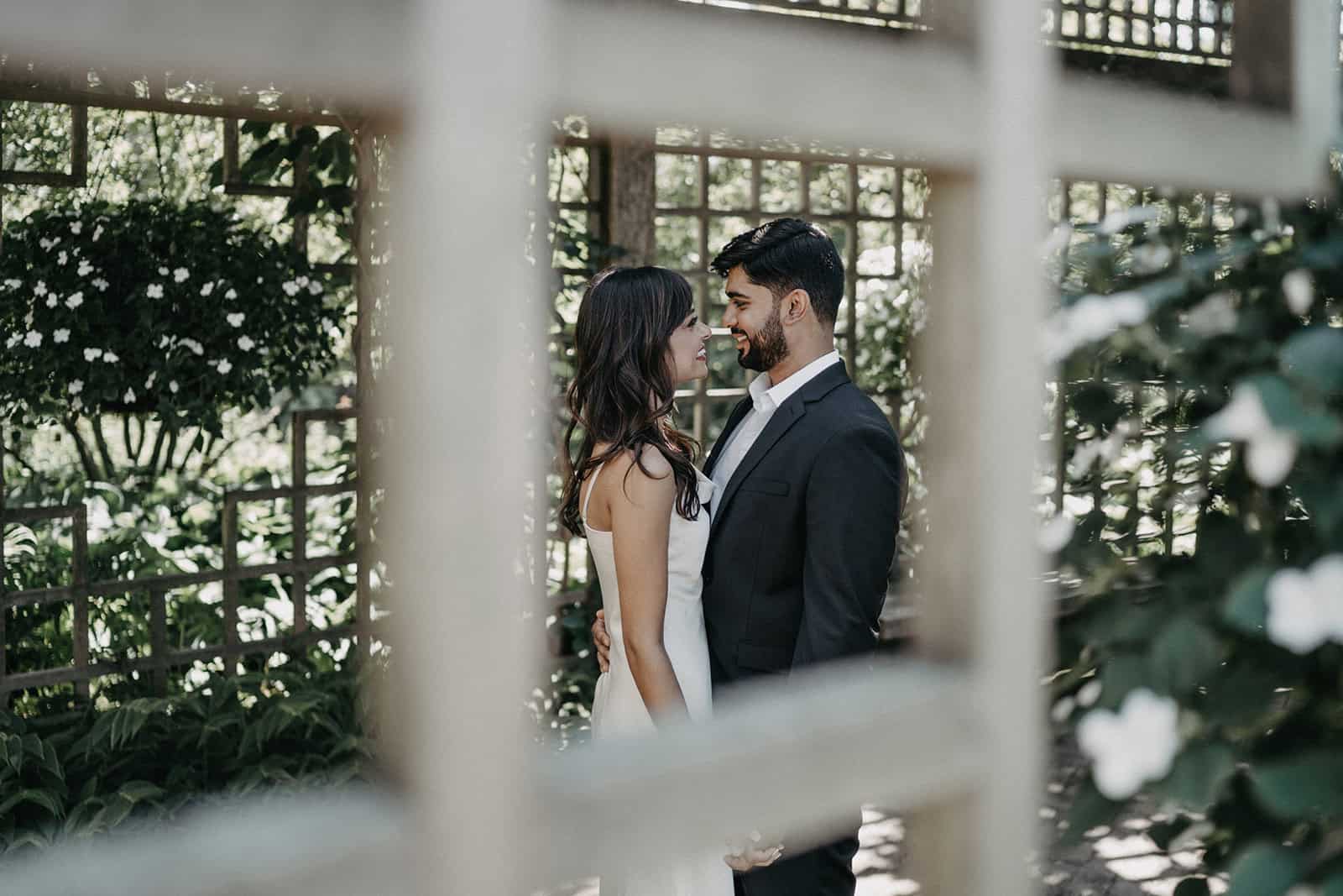Romantic couple wedding photos at luxurious outdoor venue with lush greenery and floral accents close-up shot.